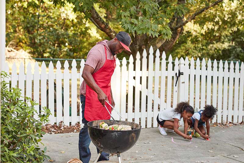 dad grilling outside with daughters